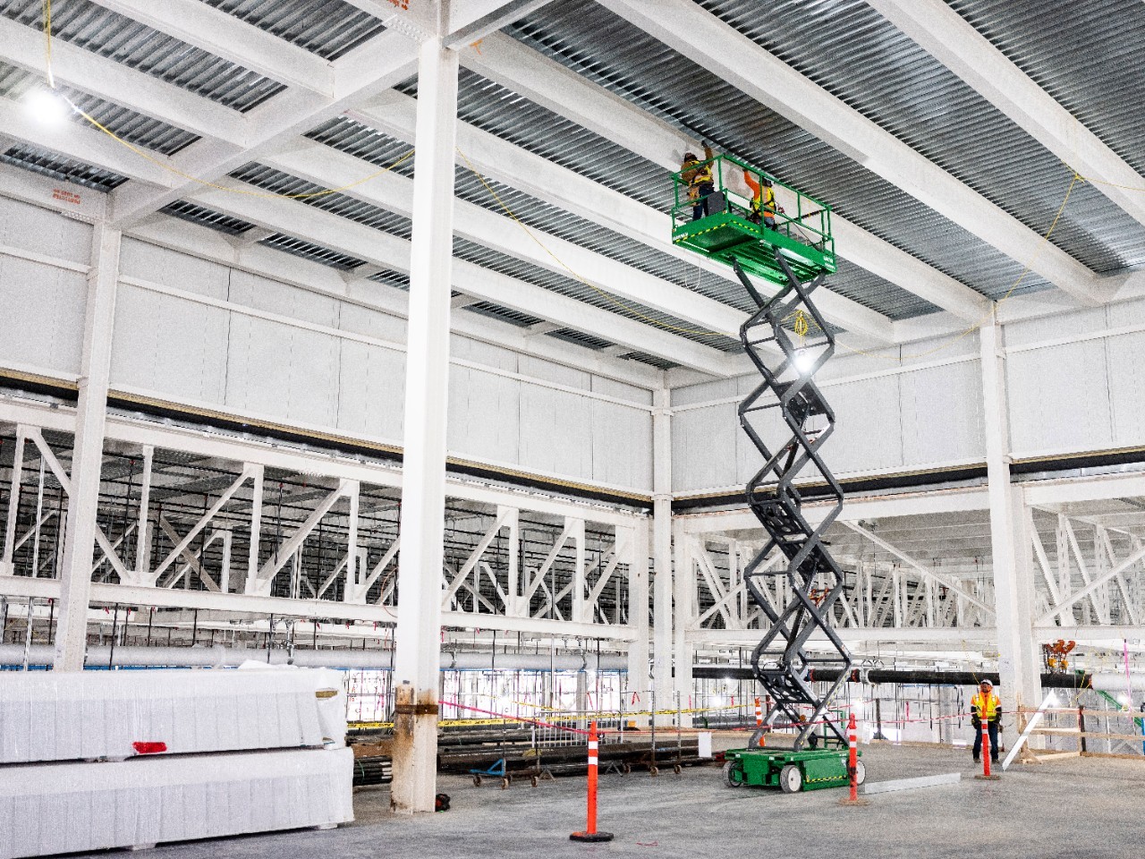 Two workers on cherry picker working on roof of Blue Oval City facility